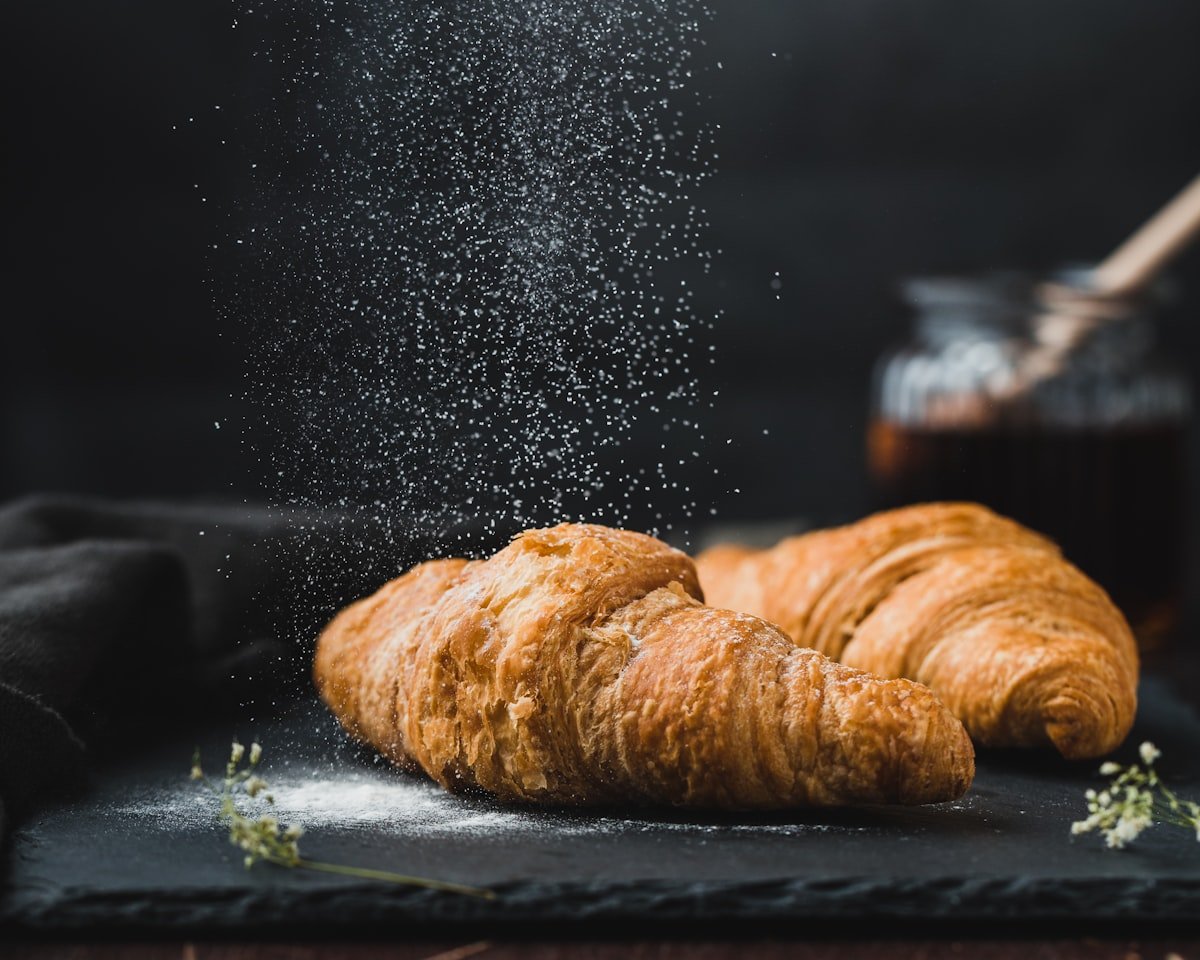 Verse croissants met poedersuiker en een potje jam